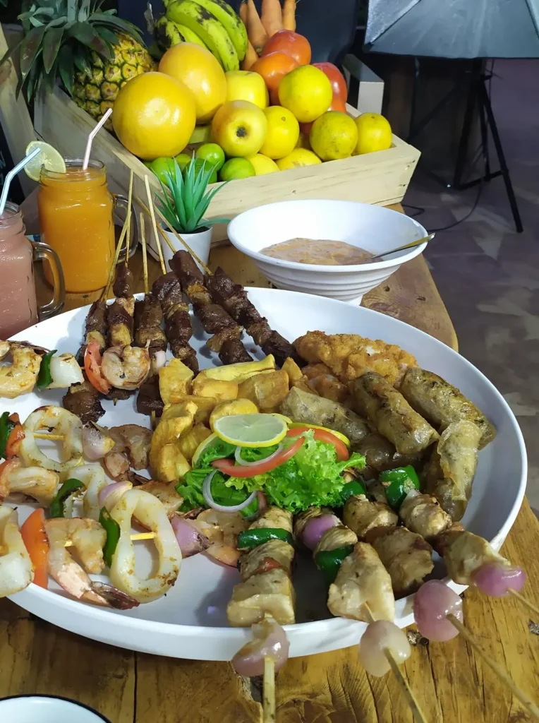 Plat de brochettes et fritures, jus de fruits et corbeille de fruits