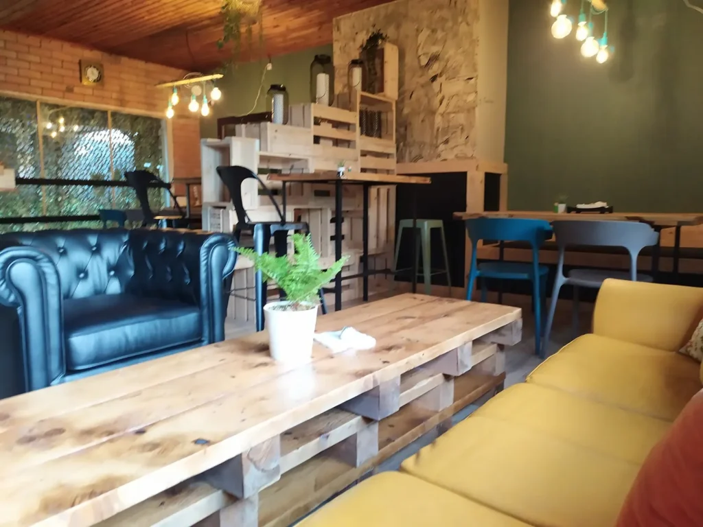 Coin salon de Tamotamo Café : fauteuil Chesterfield, canapé moutarde et table en bois de palette