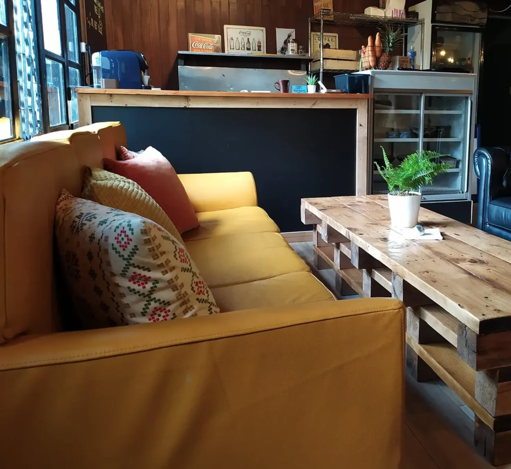 Salon avec canapé moutarde et table en palettes, face au comptoir