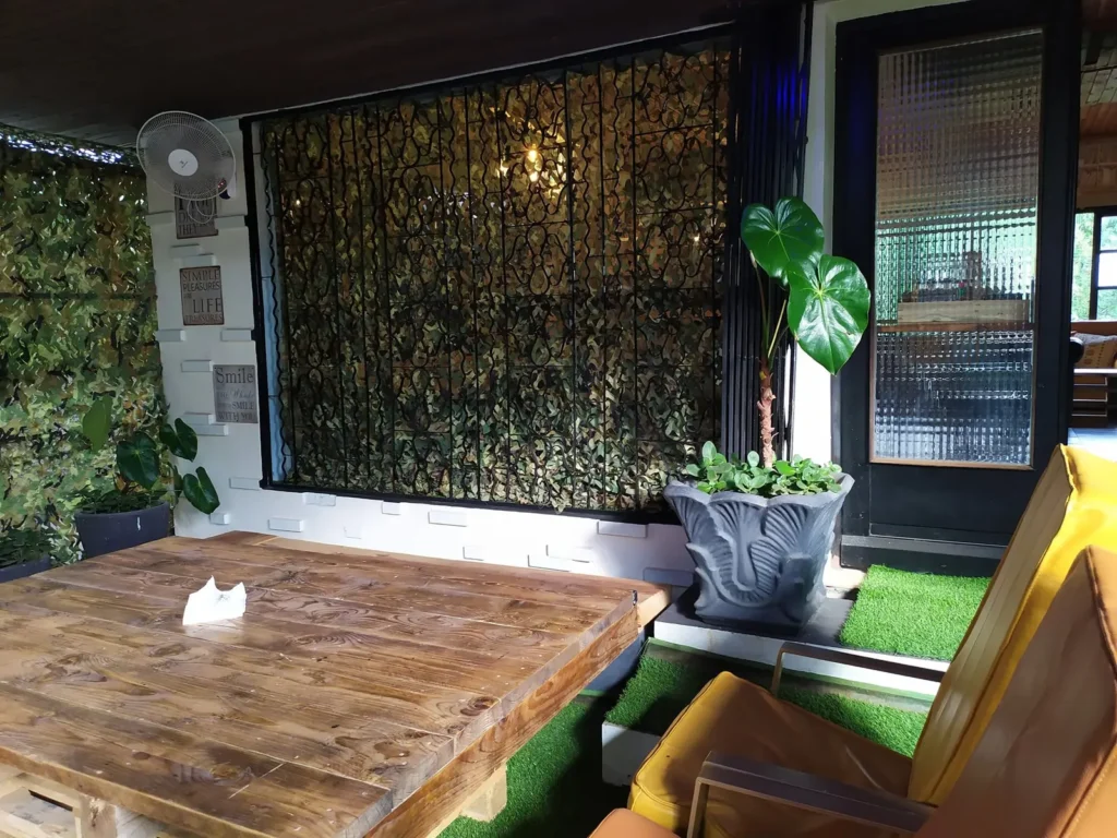 Coin de terrasse avec table en bois, mur décoré et plante