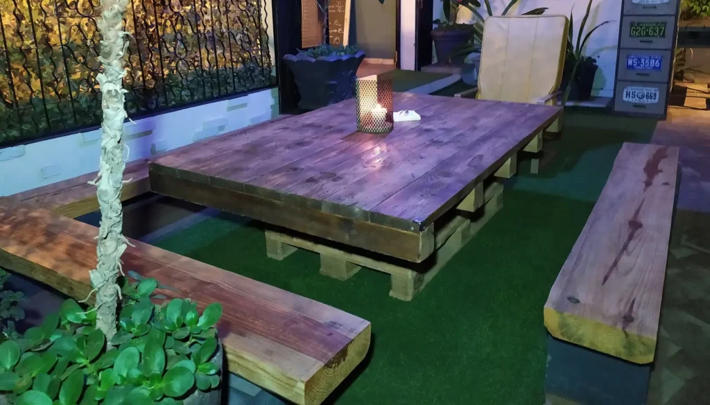 Terrasse : grande table basse en bois, bancs et gazon